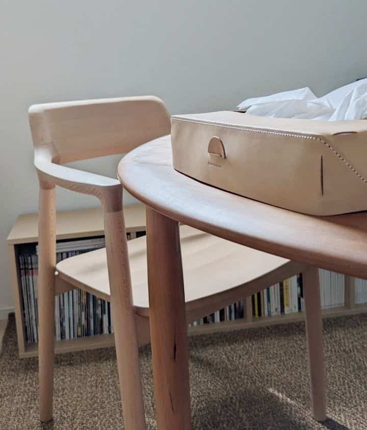Wood tones and beige leather in a dining room featuring a simple natural atmosphere with an armchair and round dining table