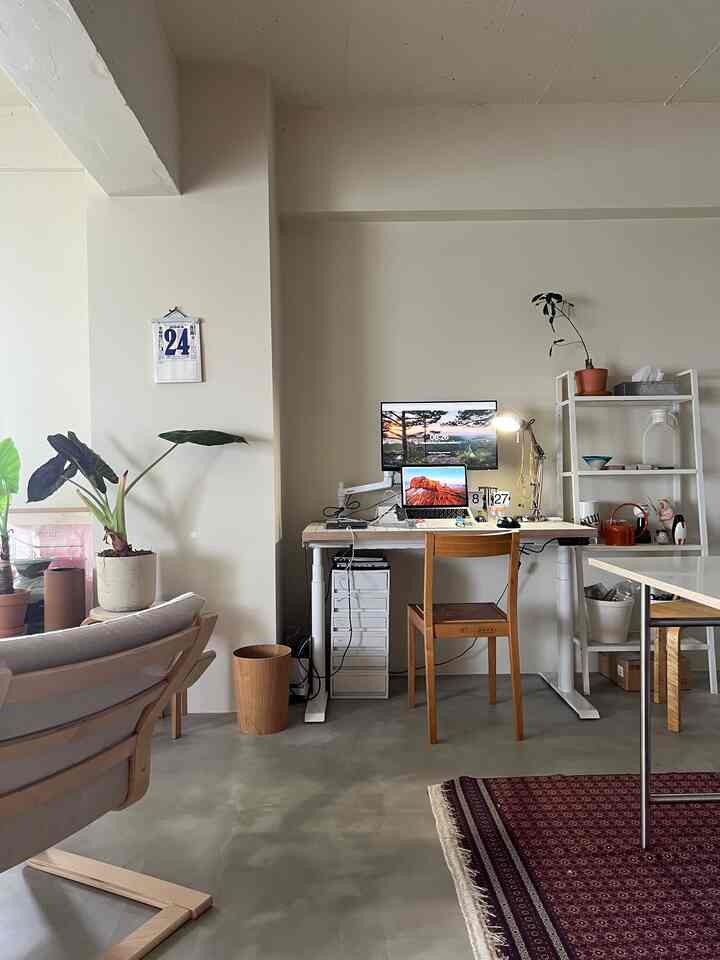 白い壁とナチュラルウッド家具が配置されたモダンなホームオフィス、植物と棚が置かれた雰囲気のあるインテリア