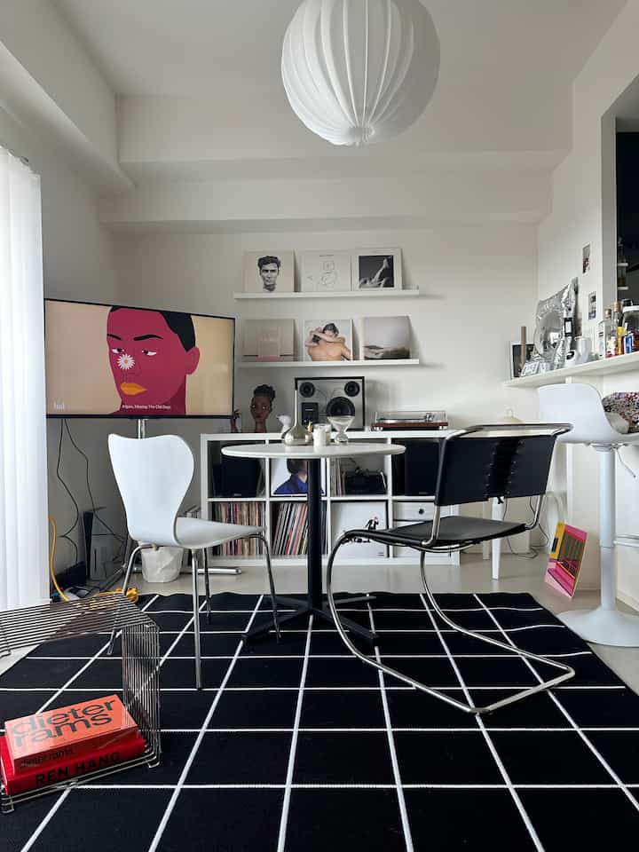 Bright white and black toned living room featuring a simple round table and Mid-Century Modern chairs in a modern space