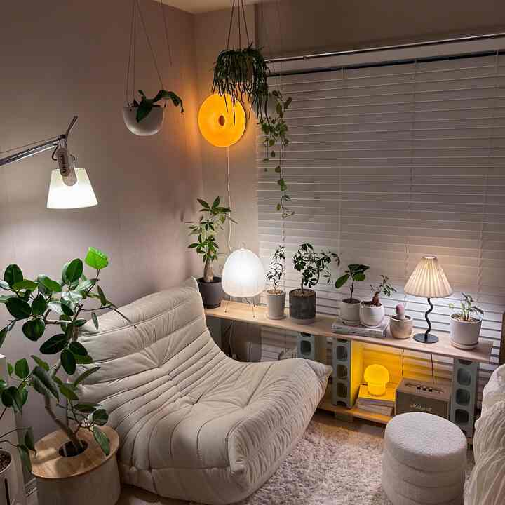 ベージュトーンのソファと複数の植物が配置された、温かみのある雰囲気のリビング