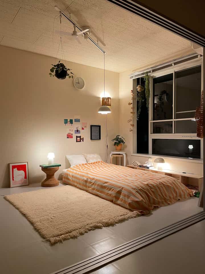 A beige and white bedroom featuring indirect lighting and striped bedspread creating a cozy atmosphere