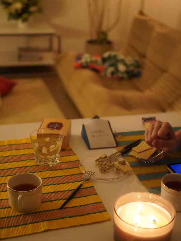 暖かい黄色と茶色の色調のリビングにソファとダイニングテーブルが配置され、キャンドルと共に居心地の良いおうちカフェの雰囲気