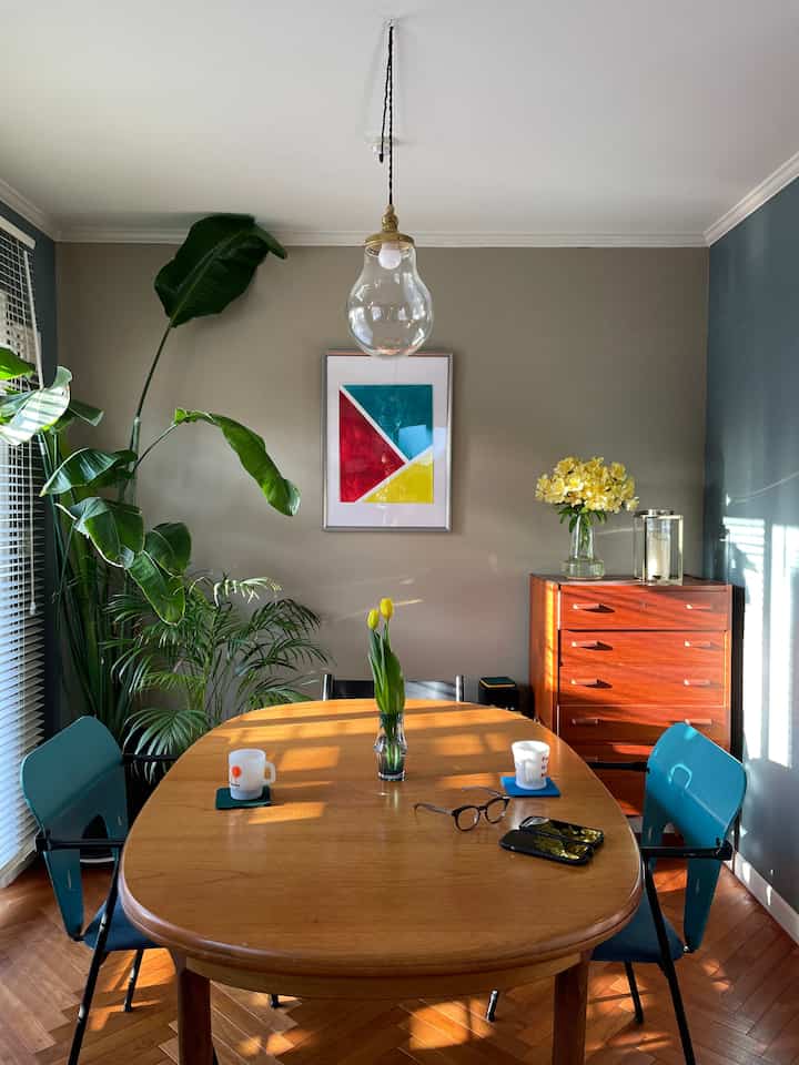 Beige-walled dining room with wood-tone dining table, featuring a vase of flowers and pendant lighting creating a warm atmosphere