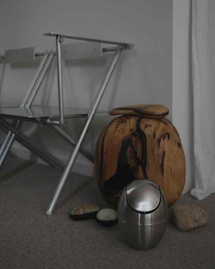 A small space featuring wood tone and silver elements, with a metal folding chair and uniquely grained wooden stool in a modern setting