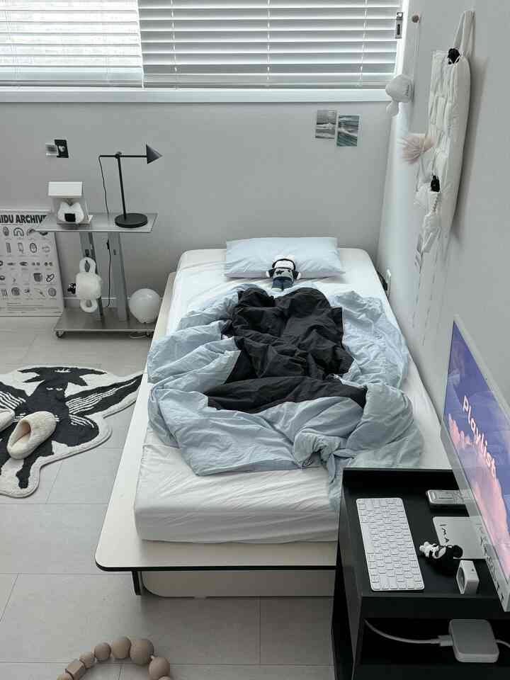 白と黒のトーンでまとめられたモダンな寝室、シンプルなベッドと寝具が配置された清潔感のある空間