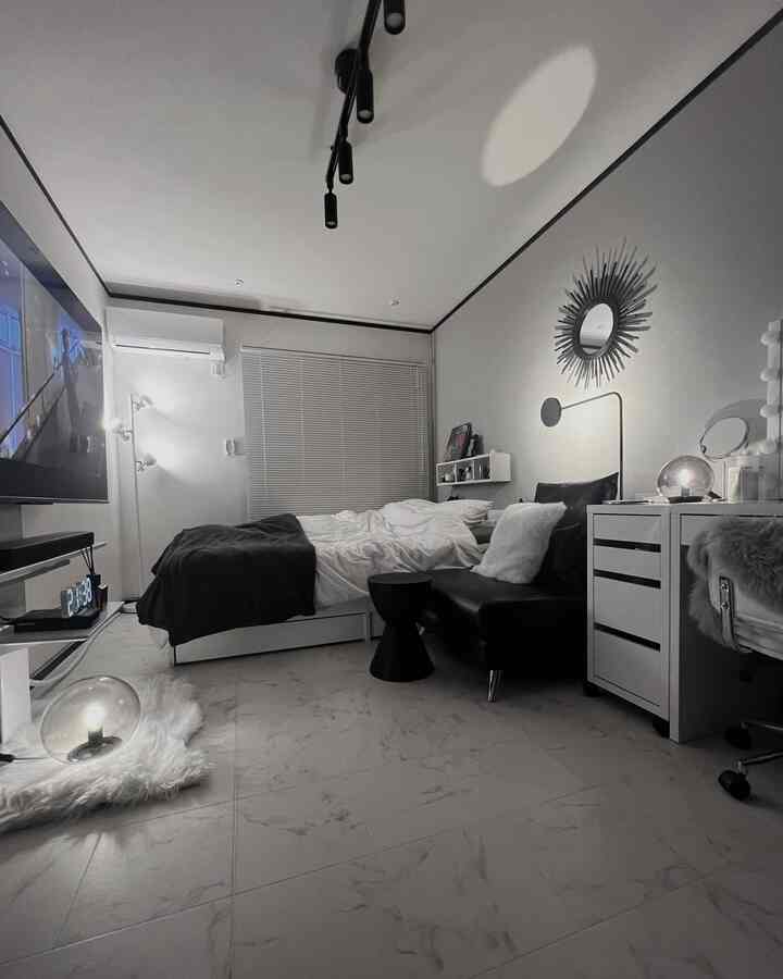 白と黒の色調が際立つモダンな寝室、ベッドとソファ、照明が配置された印象的な空間