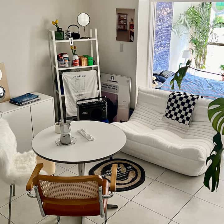 白と木目調が調和したリビング、モダンなソファと丸いコーヒーテーブルが配置された自然な雰囲気のインテリア