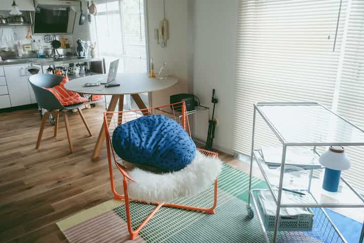 Light brown flooring and modern studio apartment featuring a round dining table and blue bean bag creating a cozy single household space