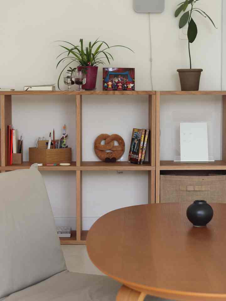 Natural-toned dining room featuring wooden dining table and shelf in a simple, orderly space