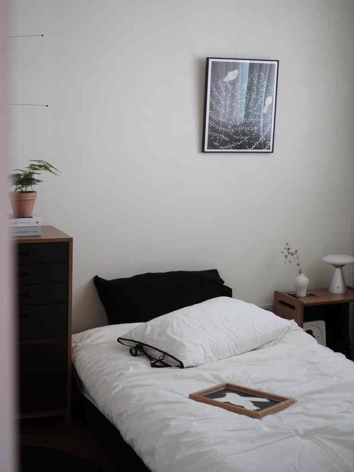 A simple modern bedroom featuring white walls and natural wood furniture with a clean aesthetic