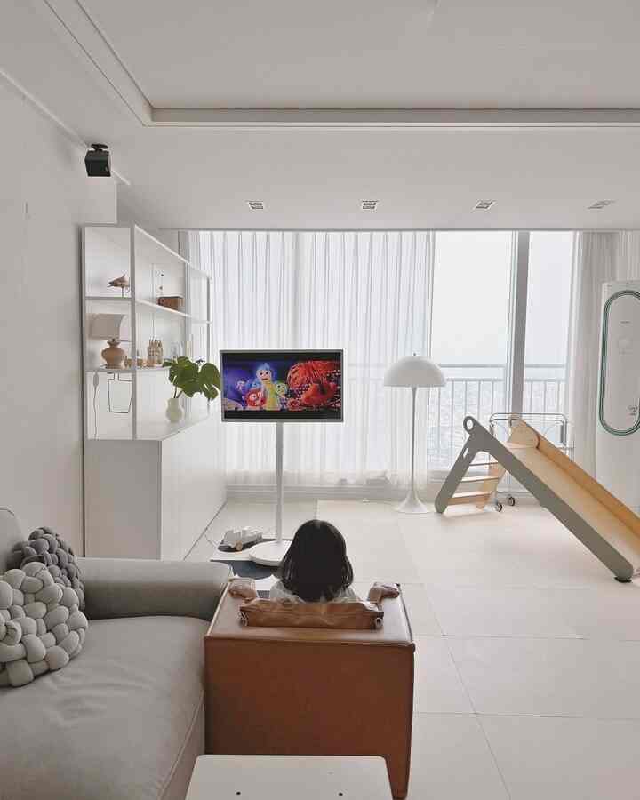 White and brown toned living room featuring a kids' slide and TV setup creating a cozy family space