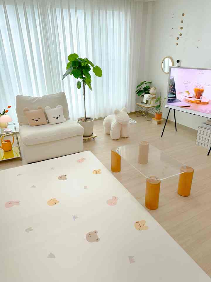 A living room with white and wood tones featuring a cozy armchair with bear cushions and a decorative mobile