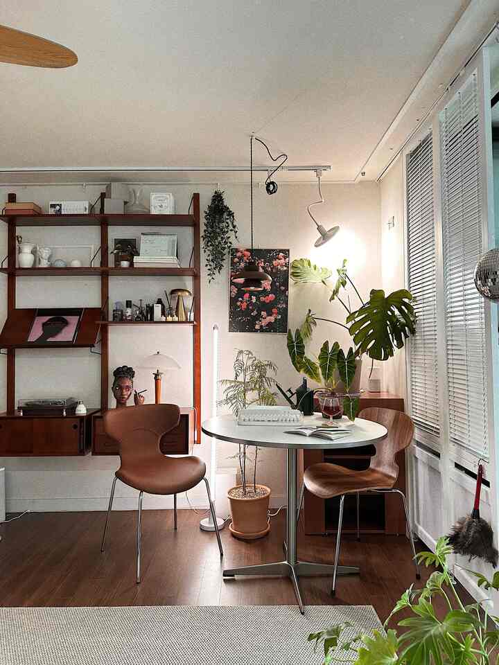 Natural-toned studio living room featuring wooden furniture and multiple plants in a cozy setting
