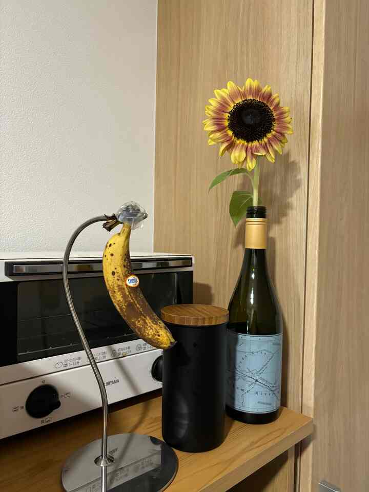 木目調のキッチン、黒いキャニスターとトースター、バナナスタンドとひまわりが置かれた雰囲気のあるおうちカフェインテリア