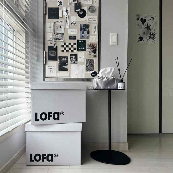 White and black toned living room corner featuring stacked white boxes and minimalist accessories with a clean atmosphere