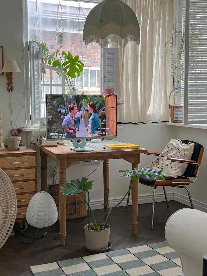 Natural wood tone and white home office space featuring a monitor and plants in a cozy living room setting