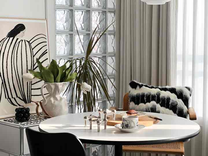 Bright white and beige living room home cafe with round Imes table, plants, and picture frame creating a calm atmosphere