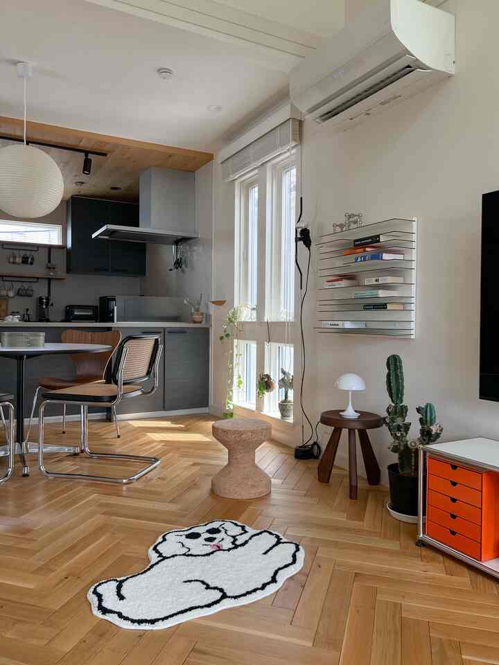Natural toned dining and living space featuring wood herringbone flooring, stools, and a minimalist kitchen creating a cozy atmosphere