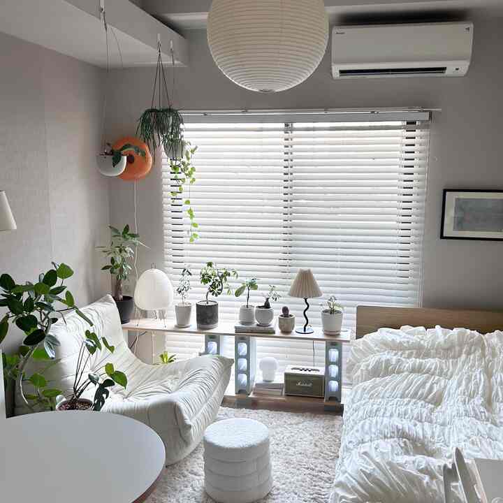 Bright white and wood-tone 1K compact room featuring multiple plants and a cozy armchair with a natural ambiance