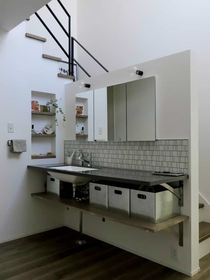 White and gray toned bathroom washbasin area featuring wall mirror and metal storage boxes with a simple design