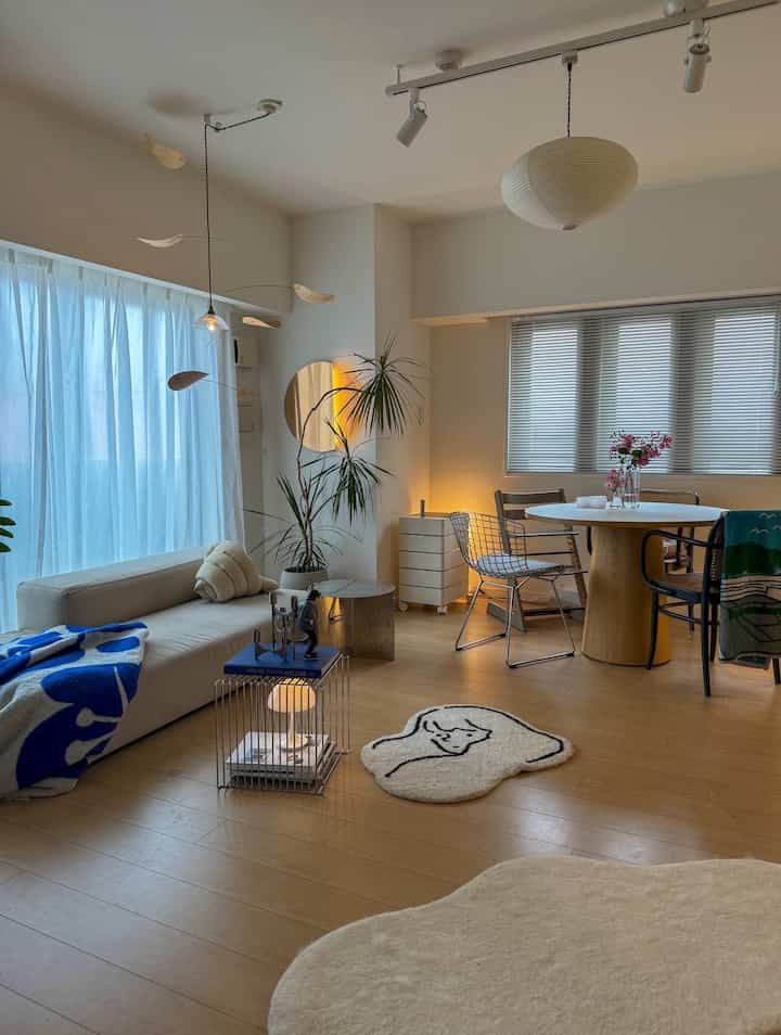 White and brown toned living and dining room featuring beige sofa, round dining table, minimalist natural modern interior