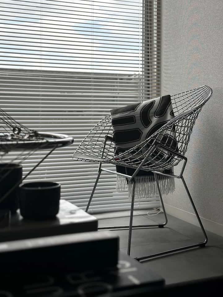 黒とグレーのトーンが支配的なリビング、金属製アームチェアと白黒のスローが配置されたミニマルでモダンな雰囲気のインテリア