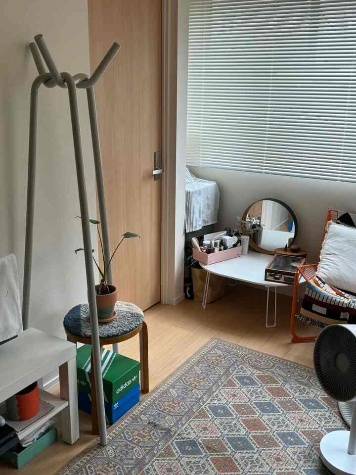 Compact entrance space with wood tones and white hues, featuring a coat rack, stool, and patterned rug with natural atmosphere