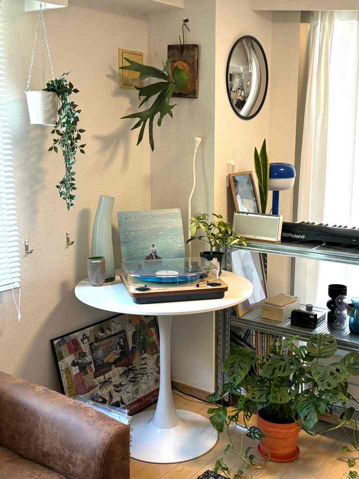White and wood tone living room with dining table, record player, and various green plants creating a cozy atmosphere