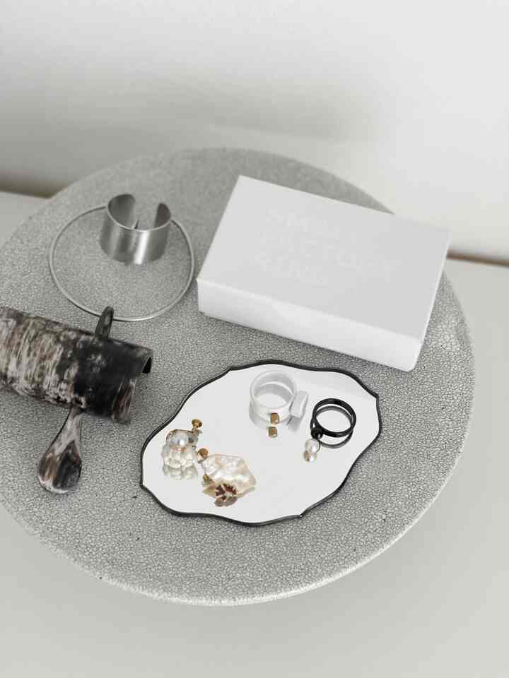 グレーとシルバーのトーンの小さなミラートレイにゴールドとシルバーのアクセサリーが整然と並べられたコンパクトな空間