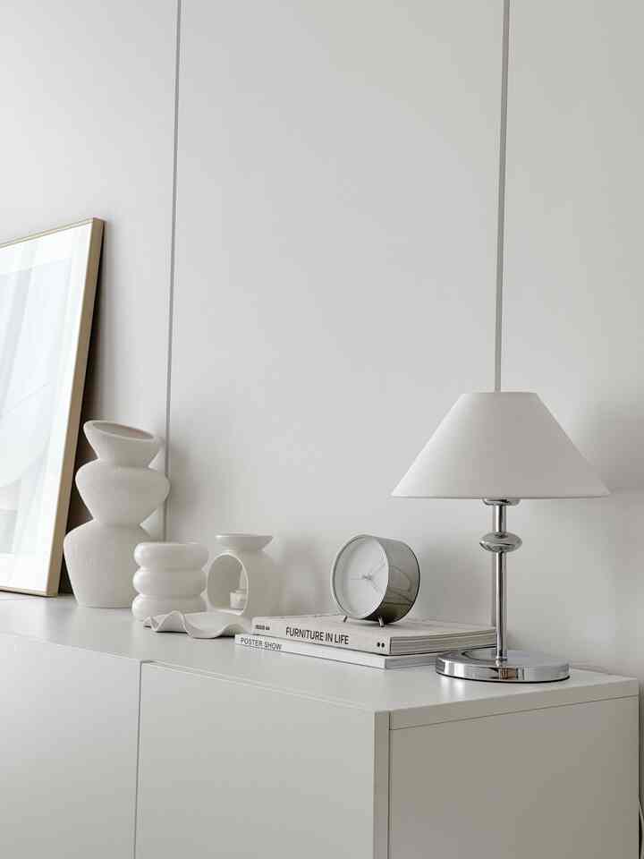 白を基調としたリビング、オブジェとシルバーのテーブルランプが配置されたシンプルでモダンなインテリア