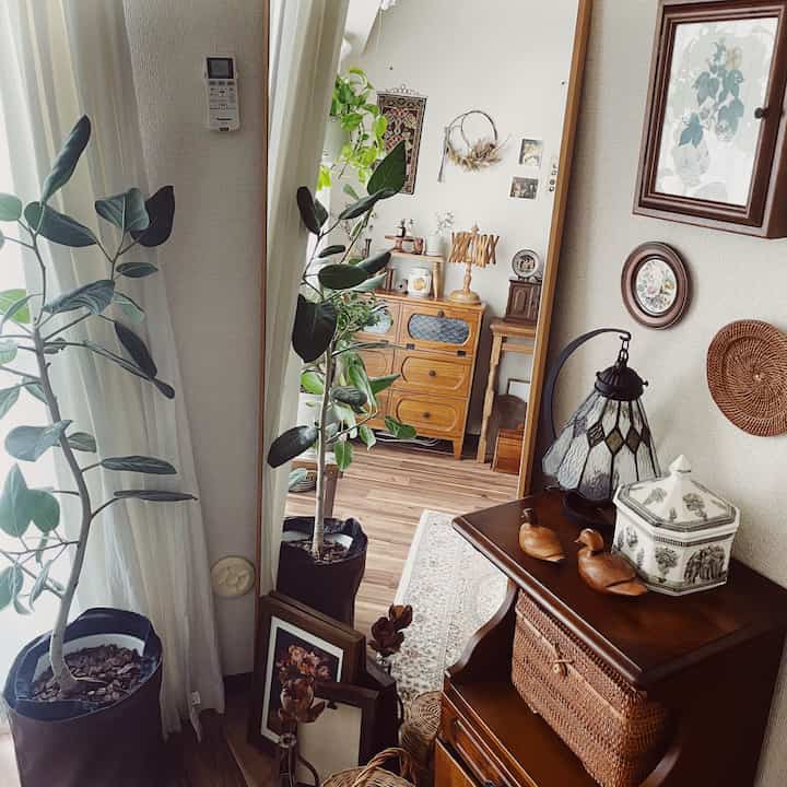 木目調とナチュラルカラーのヴィンテージ風リビング、鏡と植物が配置された雰囲気のある空間