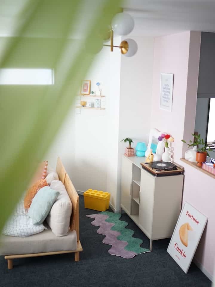 白い壁とグレーのカーペットが印象的なミッドセンチュリーモダンスタイルのリビング、木製フレームのソファと収納キャビネットが配置された雰囲気のあるインテリア