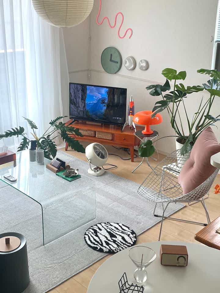 グリーンとオレンジのアクセントが映えるミッドセンチュリーモダンのリビング、テレビ台とレイアウトが印象的な居心地の良い空間