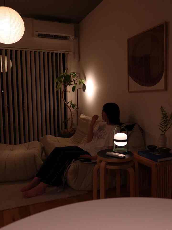 暖かいナチュラルな色調のリビング、白い大きなソファと間接照明が配置された雰囲気のある空間