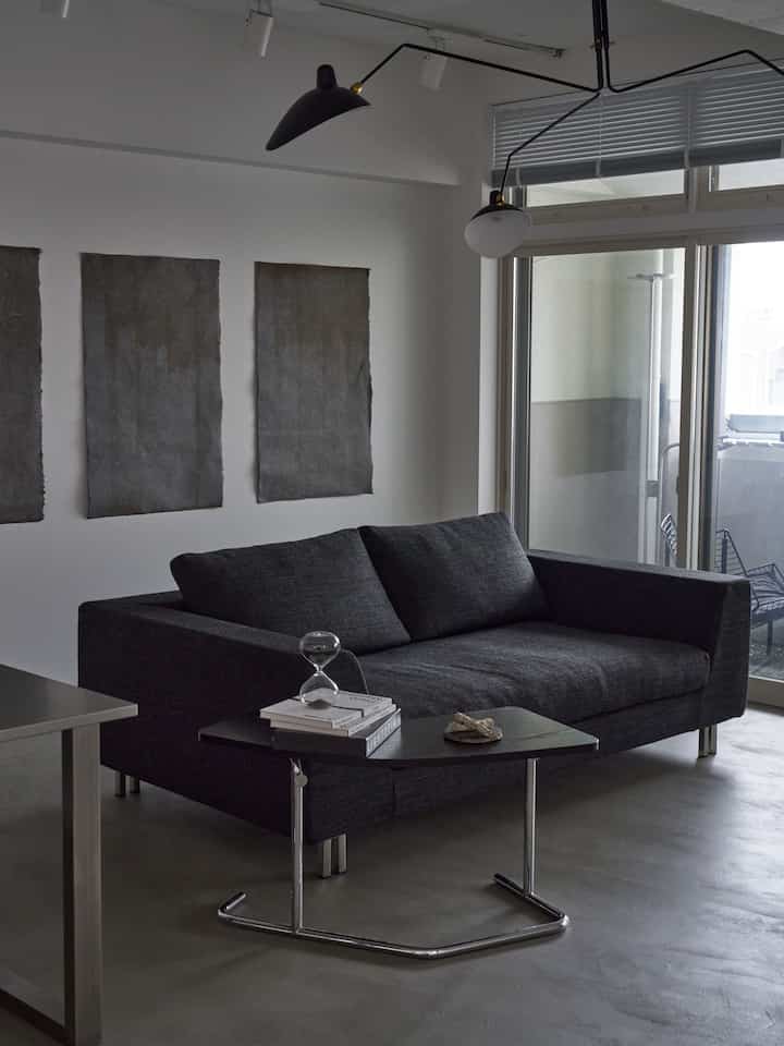 Gray-toned modern living room featuring a dark gray sofa, side table, and pendant ceiling light in a minimalist setting