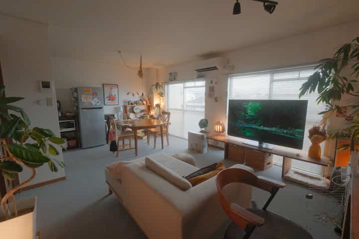 ナチュラルトーンと白い壁の12畳リビング・ダイニング、ベージュのソファと木製ダイニングテーブルが配置された雰囲気のあるインテリア