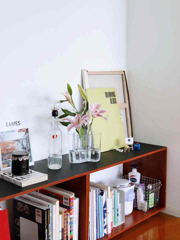 ナチュラルカラーのコーナー収納に花瓶とオブジェが配置されたミニマルな書斎空間