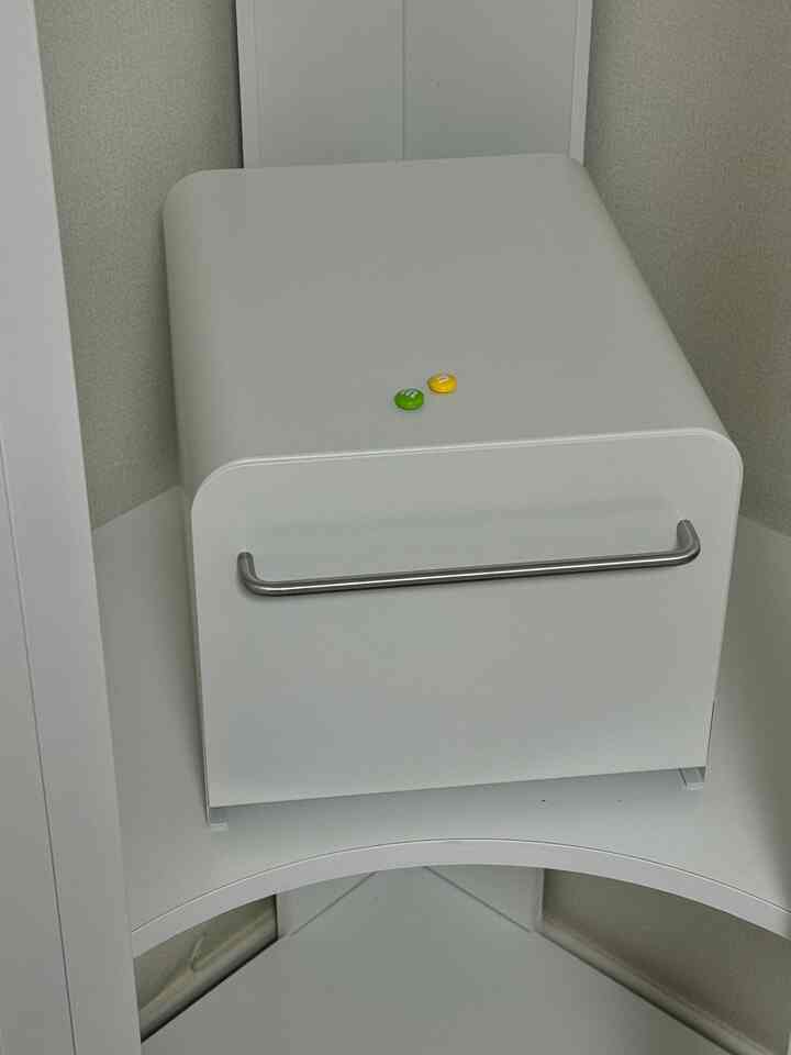 アイボリー色のコーナーに配置されたスライド式金属棚が置かれた整頓された収納スペース