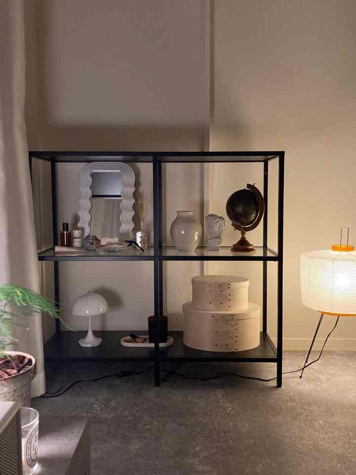 Monotone living room featuring black metal shelves, simple objets, and cozy mood lighting