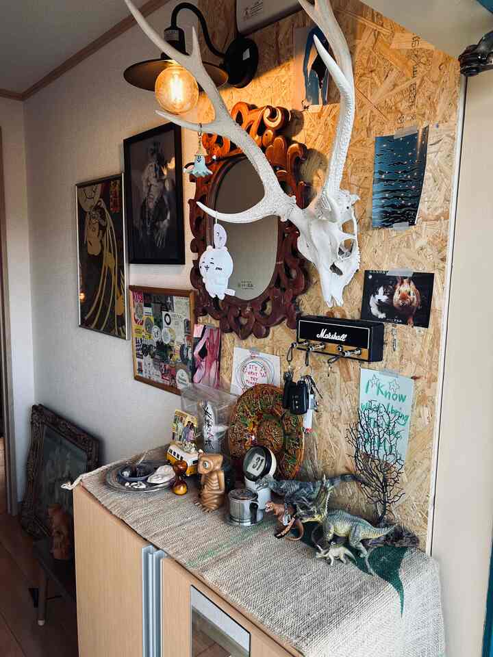 ブラウンとナチュラルカラーの玄関、DIYの壁と多様な装飾オブジェが配置された雰囲気のあるインテリア