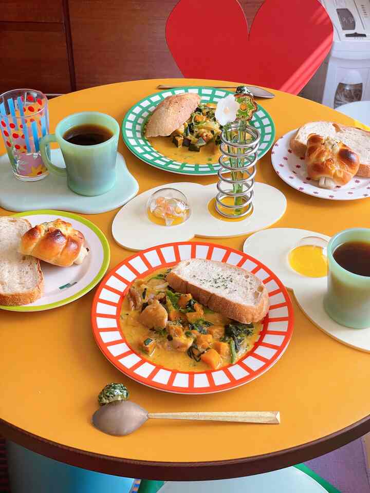 A cozy dining space featuring a yellow round table with retro-style colorful patterned plates and cups arranged neatly