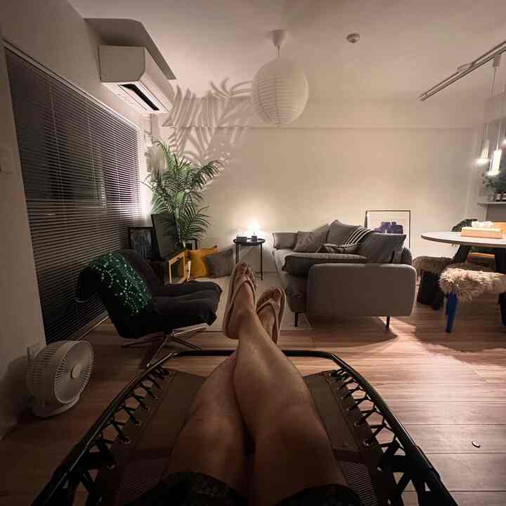 白い壁とブラウンの木目調床のリビング、グレーのソファとアームチェア、ダイニングテーブルが配置された雰囲気のあるモダンな空間