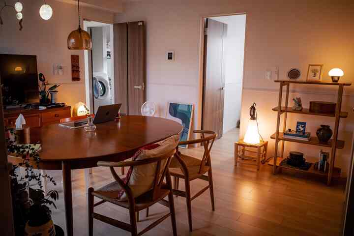 Warm wood tone and white dining and living room space featuring a round dining table, chairs, and cozy lighting