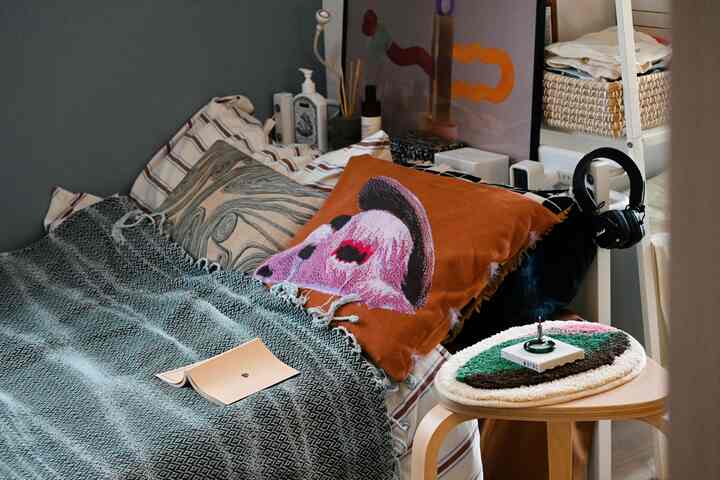 Gray and orange toned bedroom featuring colorful cushions and a poster, creating a cozy atmosphere