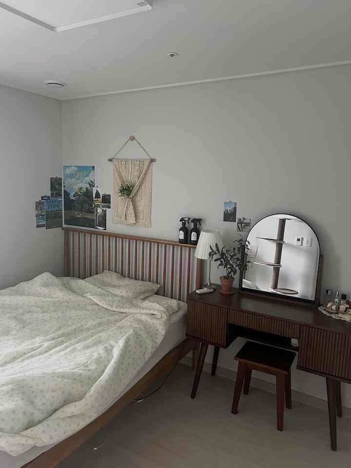 Cozy bedroom with natural wood tones and white walls featuring a wooden bed and vanity, creating a comfortable atmosphere