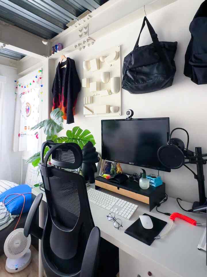 白と黒の落ち着いたトーンのコンパクトなホームオフィス、デスクとオフィスチェア、モニター、観葉植物が配置された実用的なインテリア