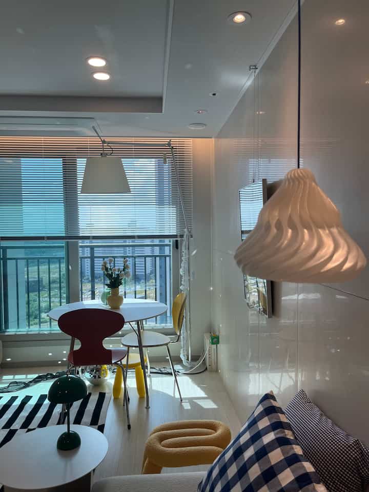 白と黄色が調和するモダンな二人用ダイニングルーム、きれいなソファと多様な照明が配置された空間