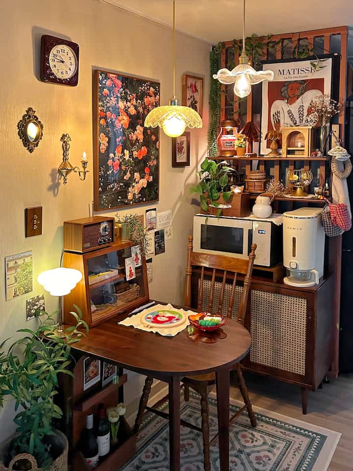 Cozy kitchen space with warm wood tones and vintage decor, featuring a wooden semicircular table under pendant lights and curated accessories