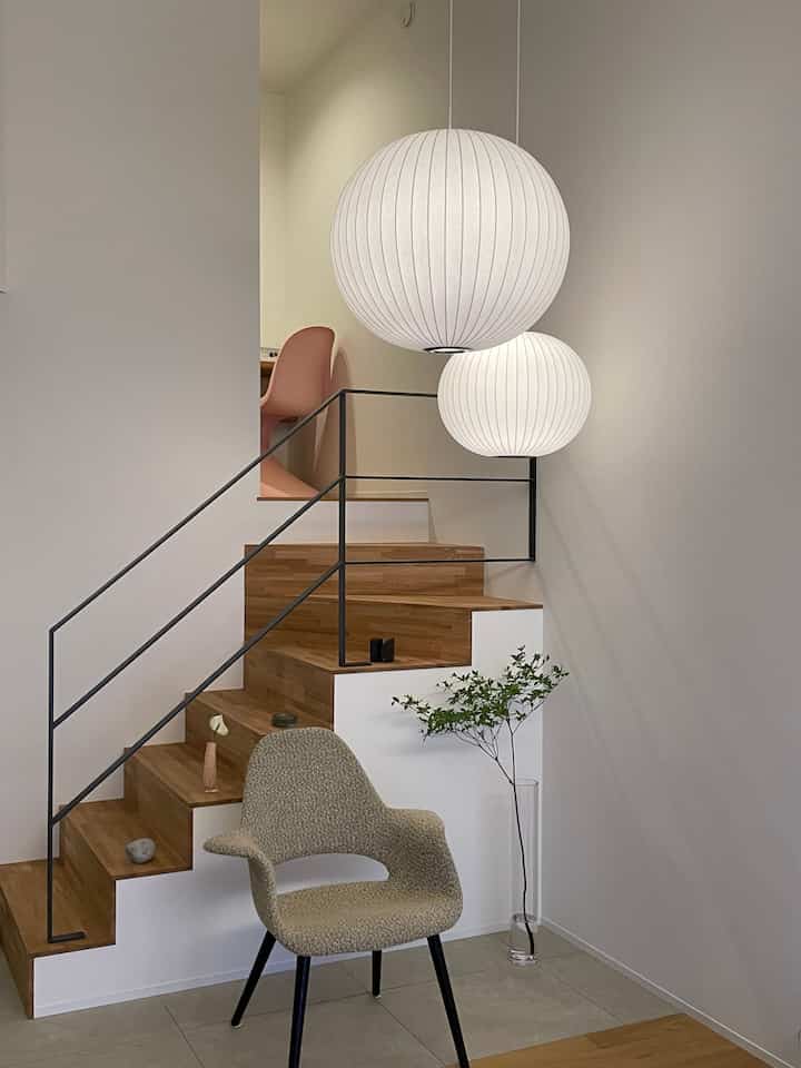 白と木目調の玄関、ミニマルデザインと大きなペンダントライトが印象的な落ち着いたインテリア