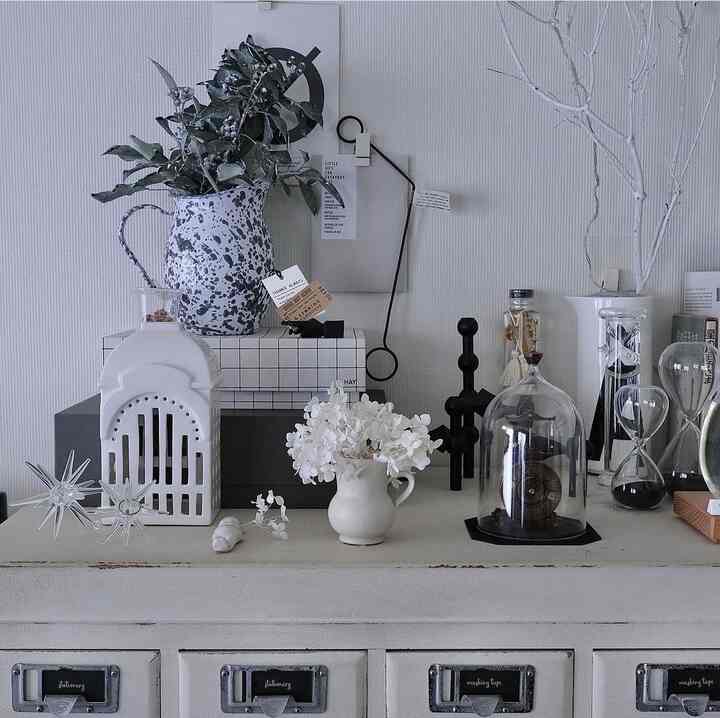 モノトーンのリビング、様々な花瓶や額縁、オブジェが配置された落ち着いた雰囲気のあるインテリア